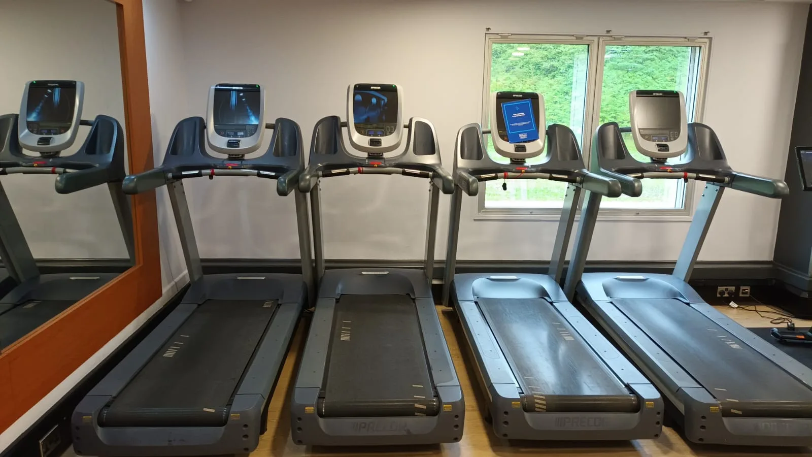 Vier Laufbänder in einem Fitnessraum mit digitalen Displays