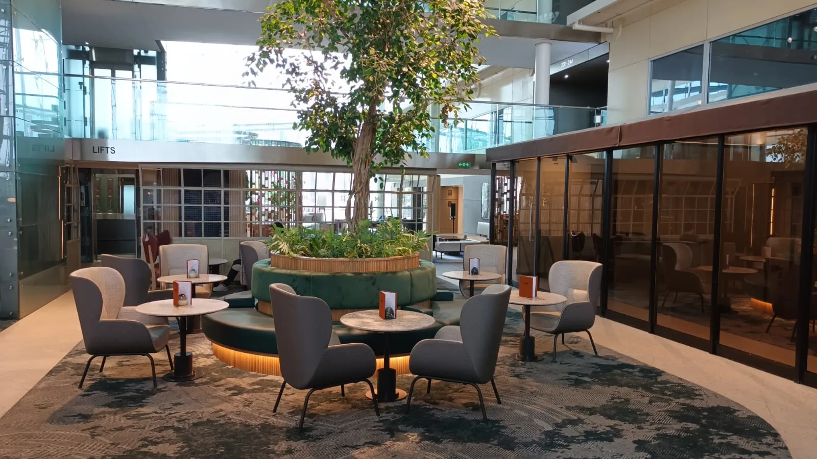 Hotellobby mit Sesseln und Tischen um Baum