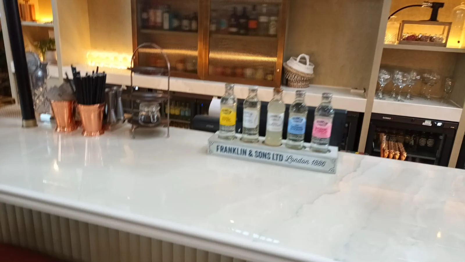 Bar mit Flaschen und Gläsern auf weißem Marmor
