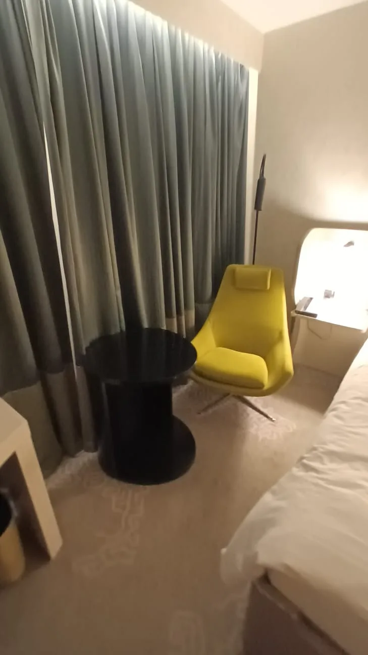 Hotelzimmer mit gelber Sessel und schwarzer Couchtisch