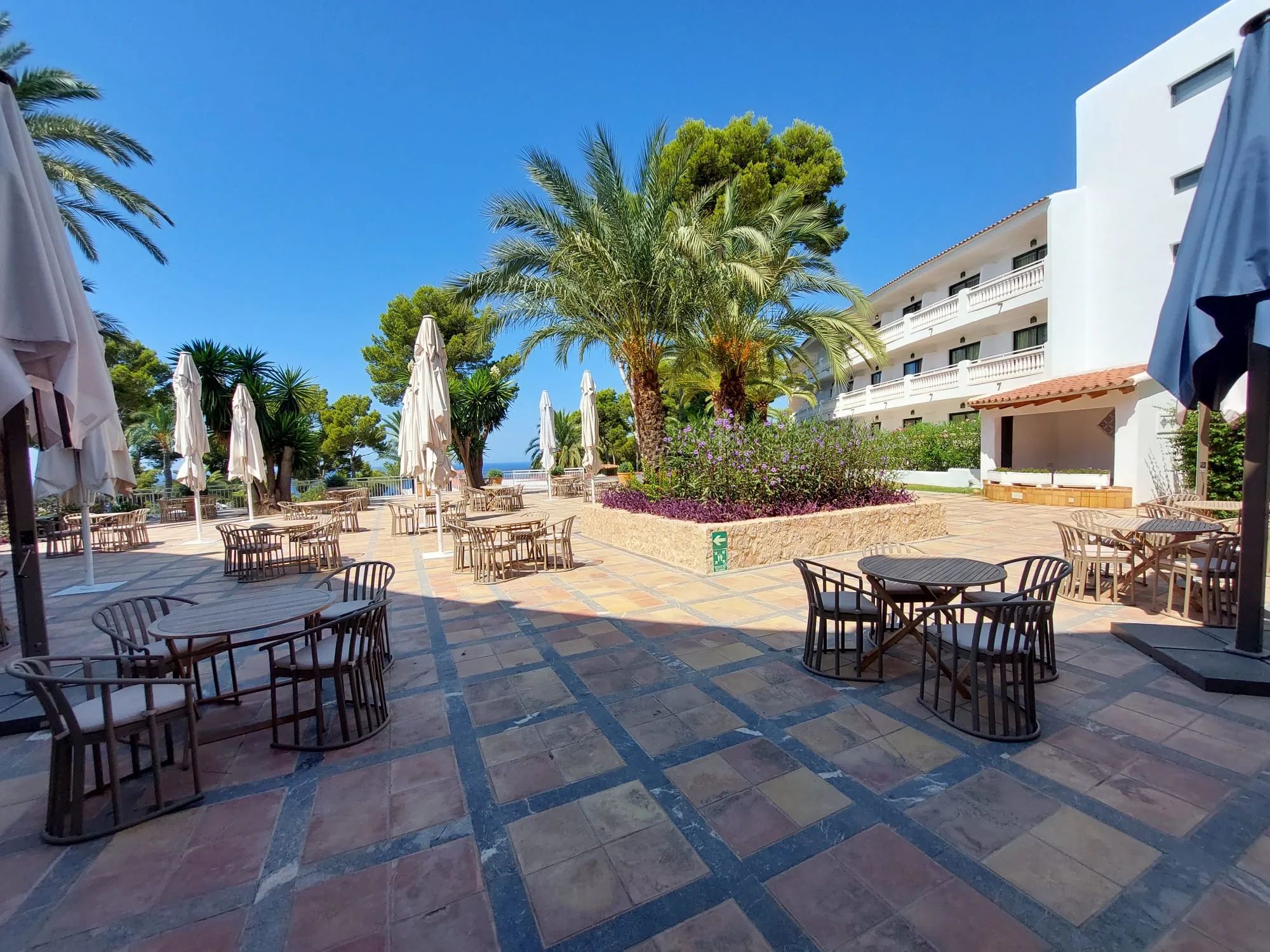 Terrasse mit Tischen und Sonnenschirmen im Hotel