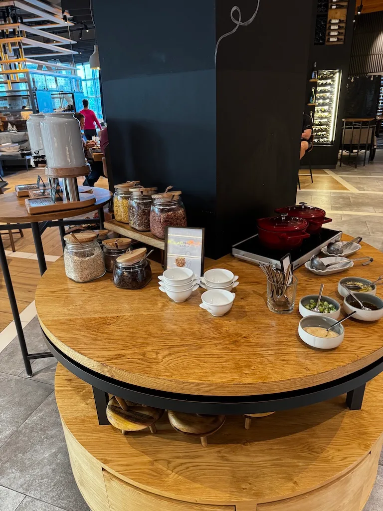Frühstückstablett mit Kaffee, Müsli und Becher auf Holztisch