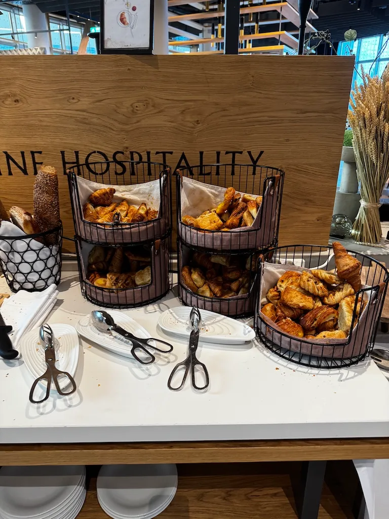 Frühstückskorb mit Croissants und Brötchen auf Holztisch