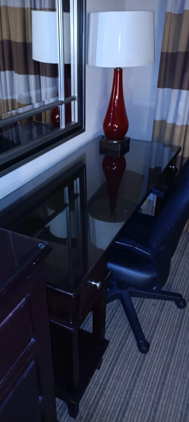 Hotelzimmer mit Schreibtisch, Stuhl und rotem Lampenschirm