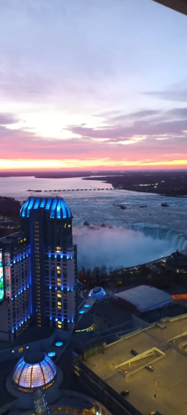Hotel mit blau beleuchteter Kuppel und Niagara-Fälle bei Sonnenuntergang