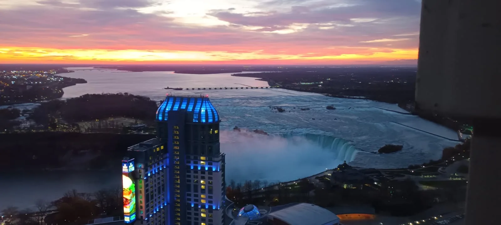 Hilton-Hotel mit beleuchteter Fassade am Niagara-Falls bei Sonnenuntergang