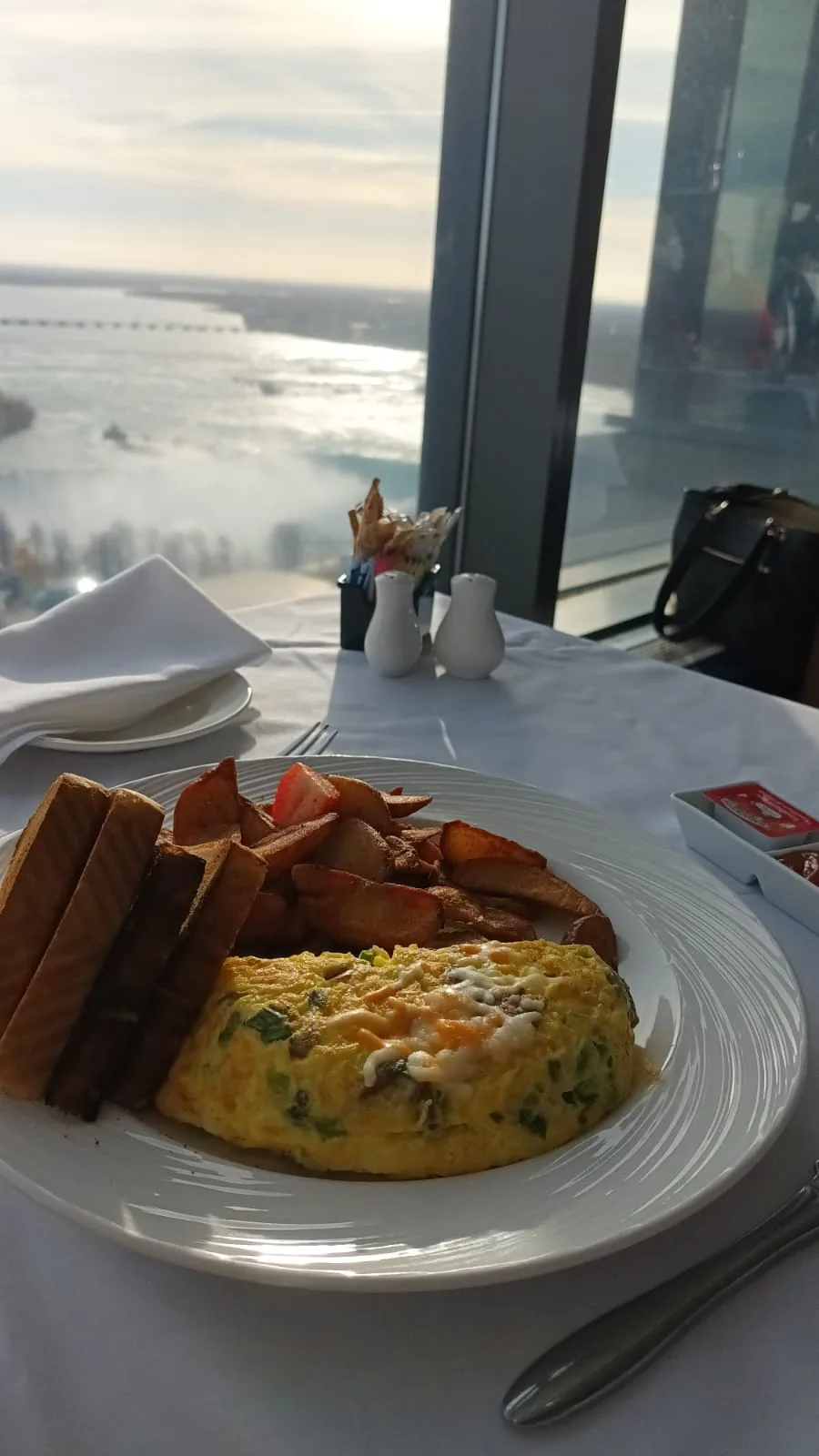 Omelett mit Kartoffeln und Brot auf Teller vor Fenster mit Blick auf Niagara-Fälle
