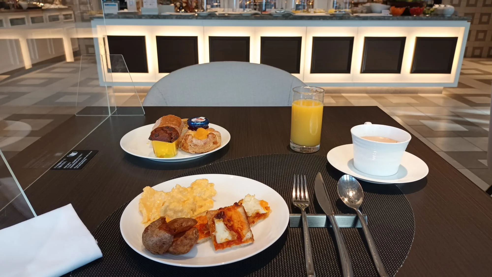Frühstückstablett mit Kaffee, Orangensaft und Brot auf einem modernen Tisch