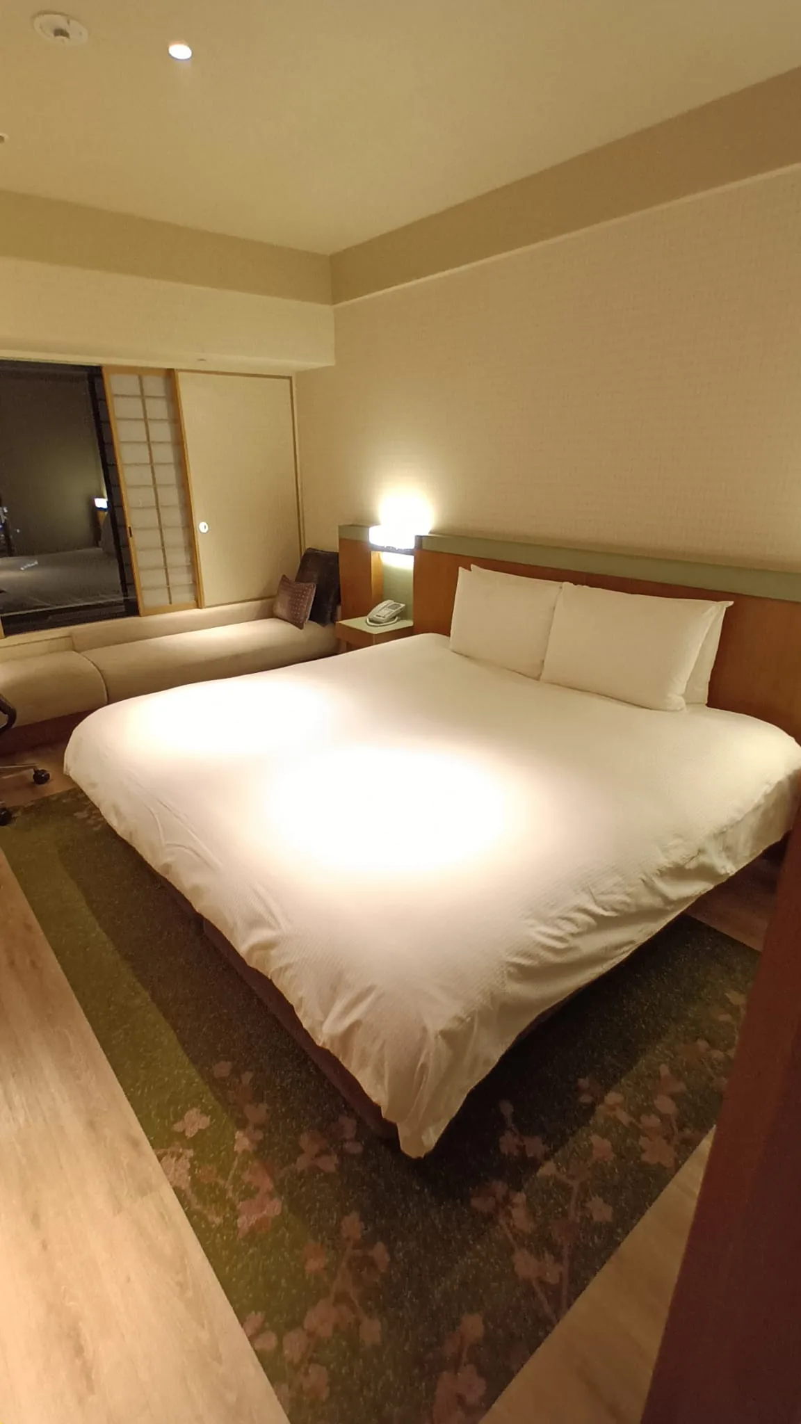 Hotelzimmer mit Doppelbett und Tagesdecke in Grautönen