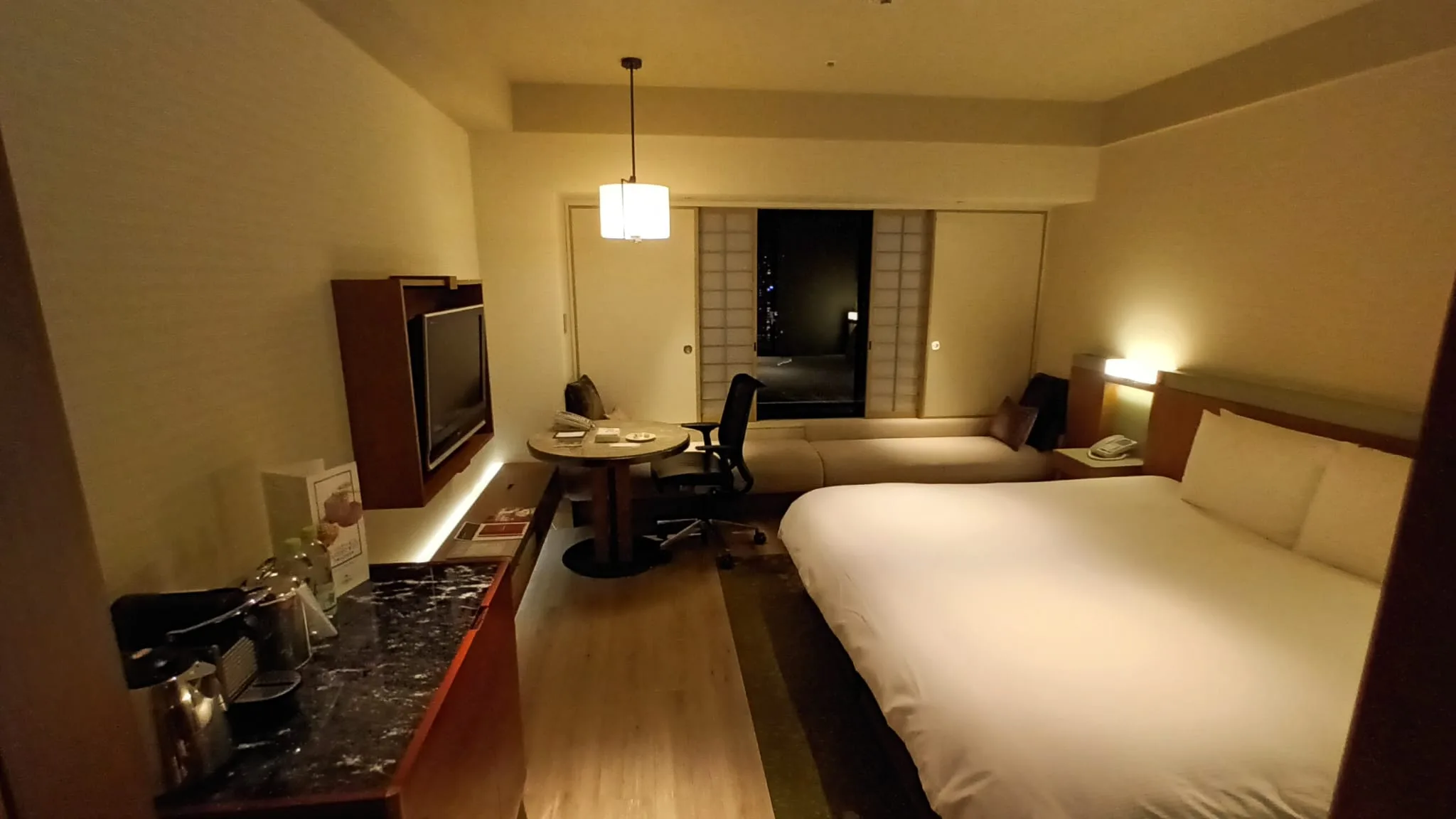Hotelzimmer mit Doppelbett und Tagesdecke in Grautönen