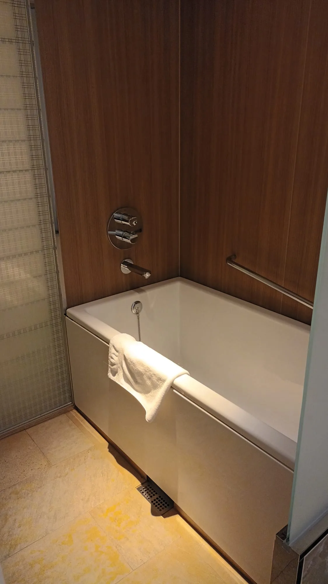 Moderne Hotelbadewanne mit Handtuch und Holzpaneelen