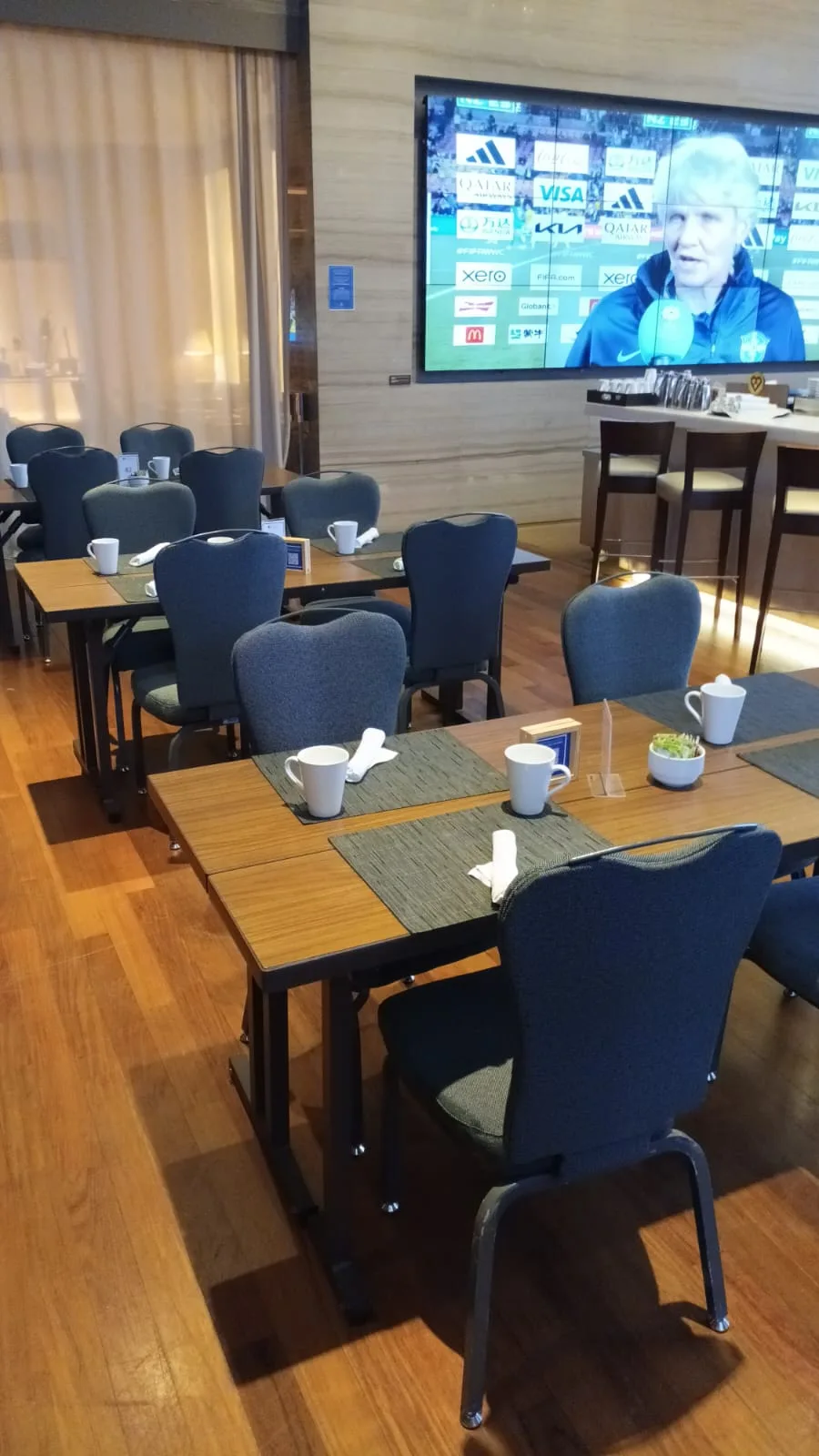 Hotelrestaurant mit Tischen und Stühlen, Fernseher im Hintergrund