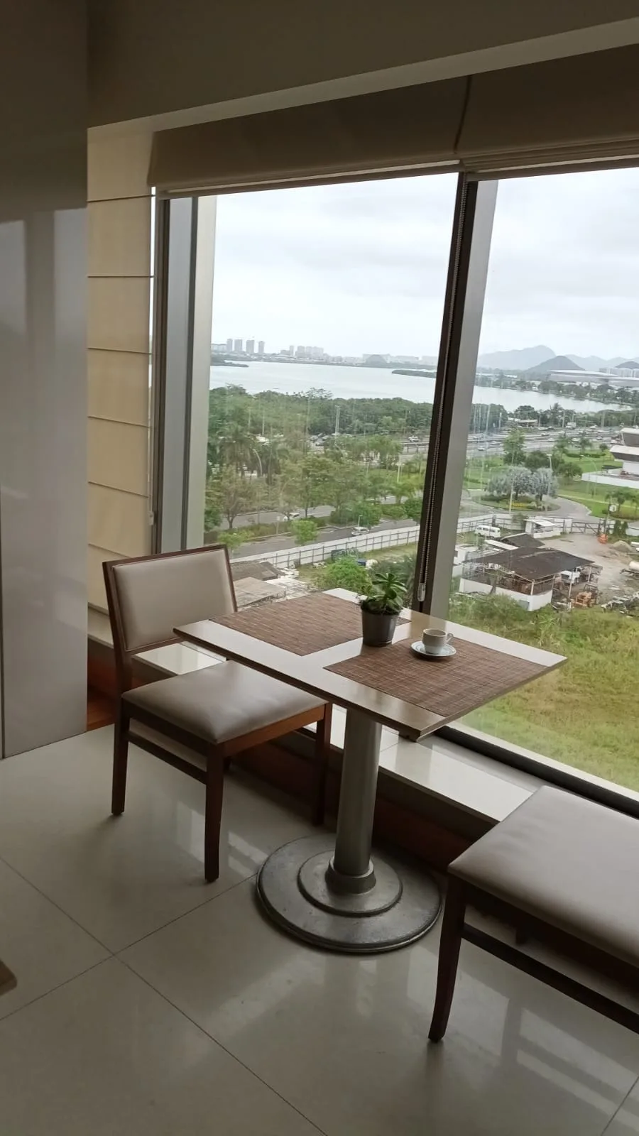 Hotelzimmer mit Tisch und Stühlen vor großem Fenster mit Blick auf Wasser und Landschaft