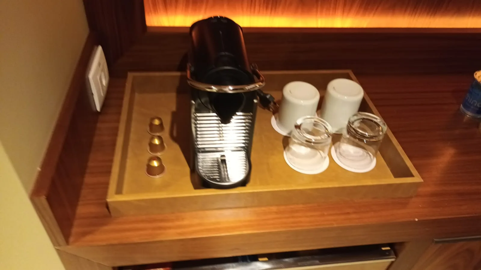Kaffeemaschine auf Holztablett mit Gläsern und Kapseln