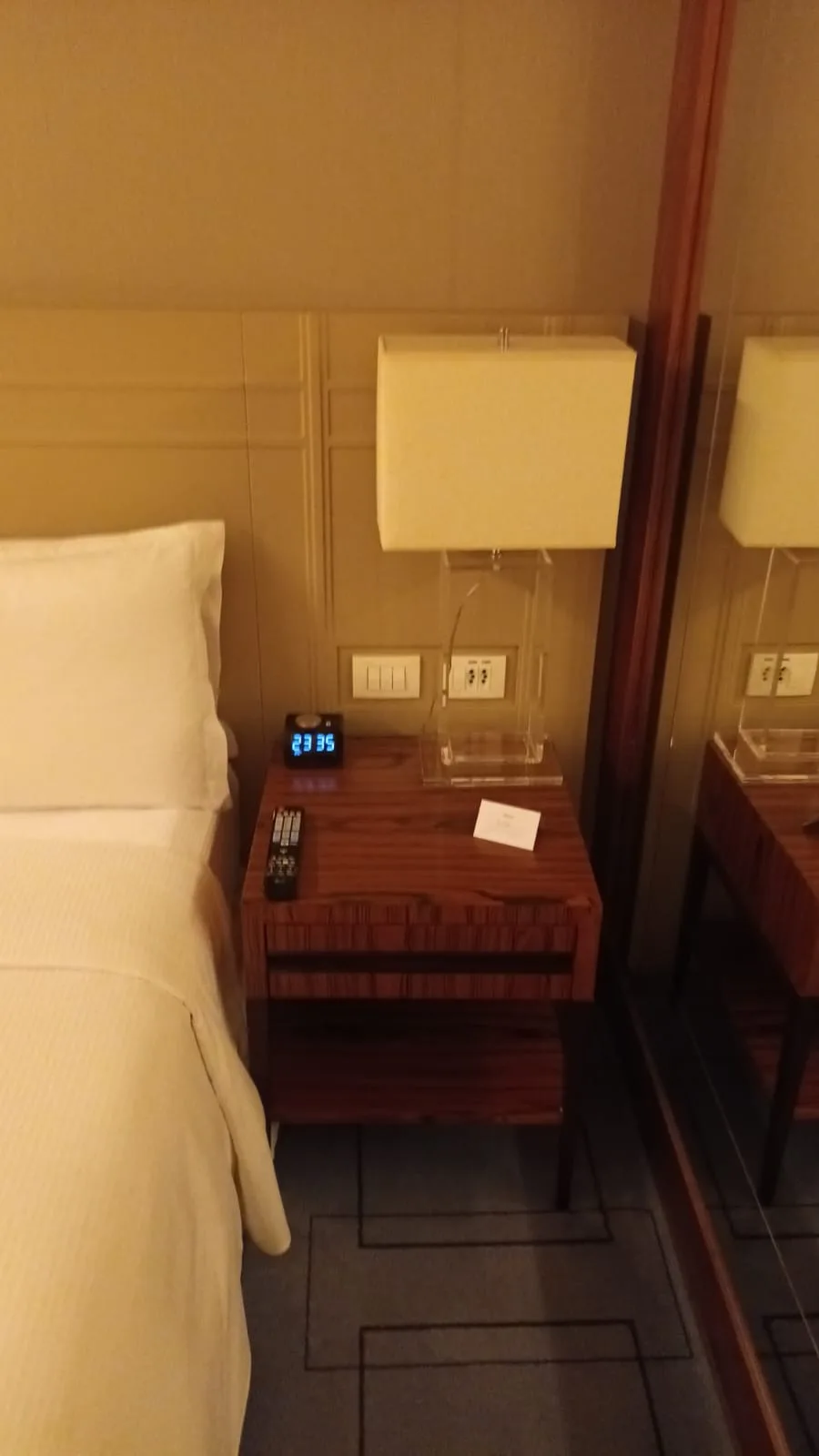 Hotelzimmer mit Nachttisch, Uhr und Steckdosen