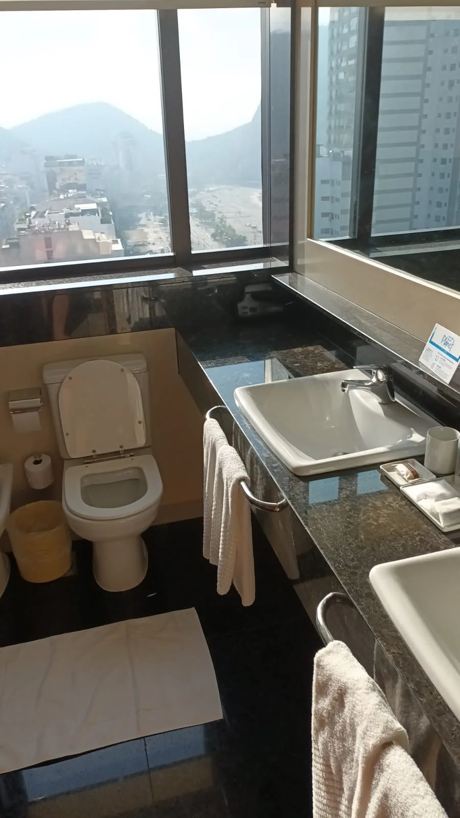 Badezimmer mit Toilette und Waschbecken mit Blick auf Stadt und Berge