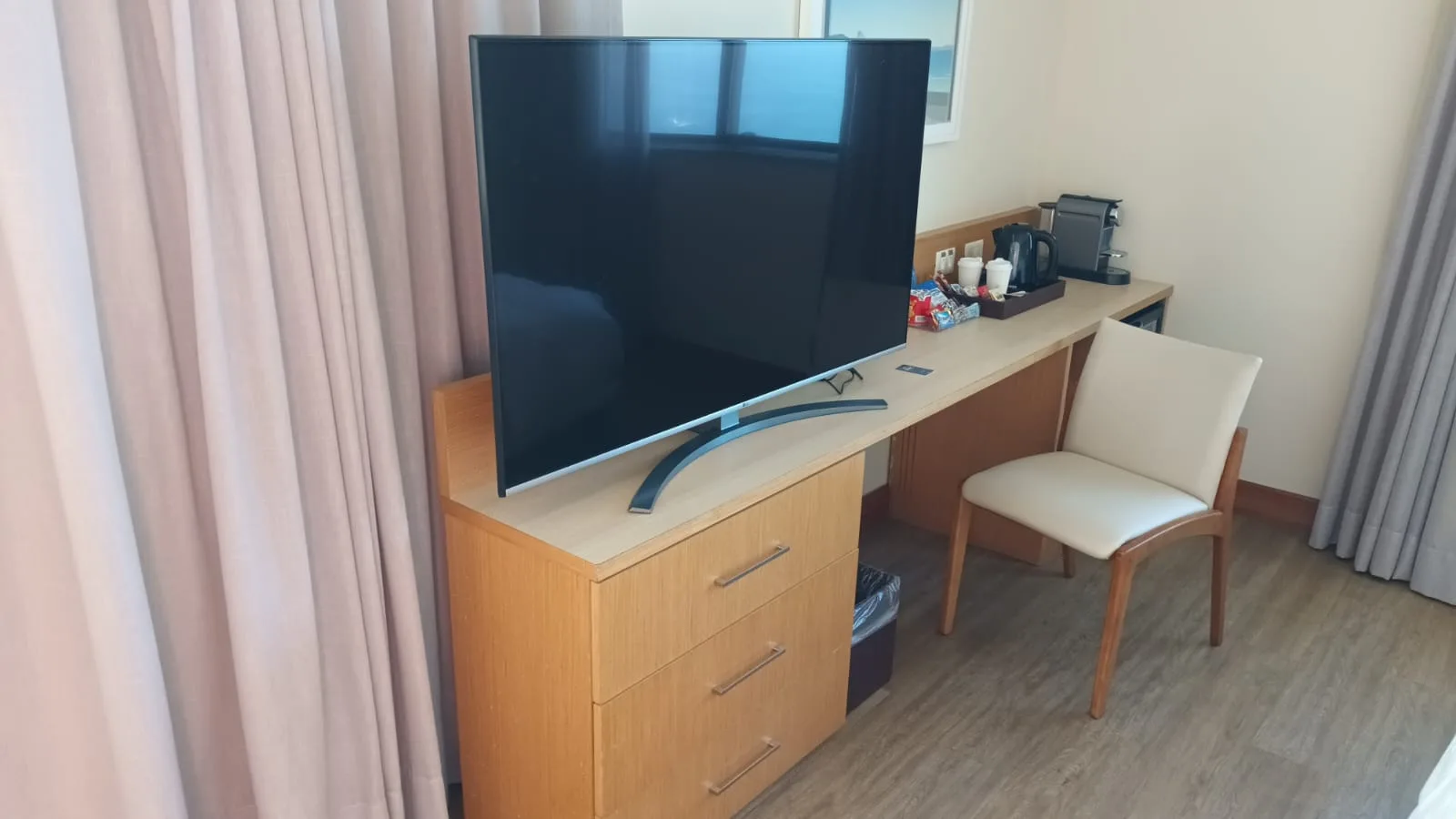 Hotelzimmer mit Flachbildfernseher auf Holzkommode