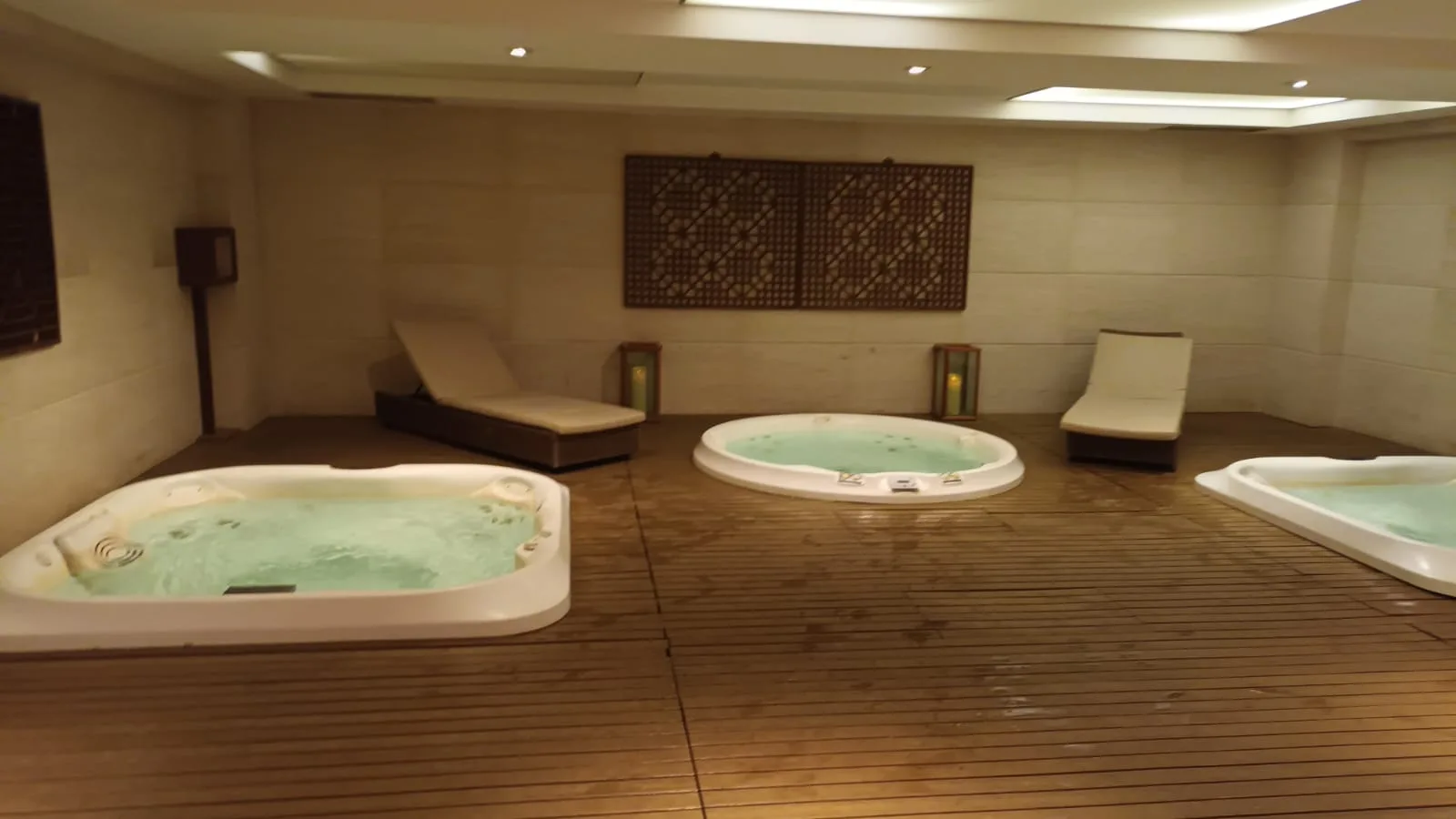 Drei Whirlpools in einem Wellnessbereich mit Holzboden und Liegen