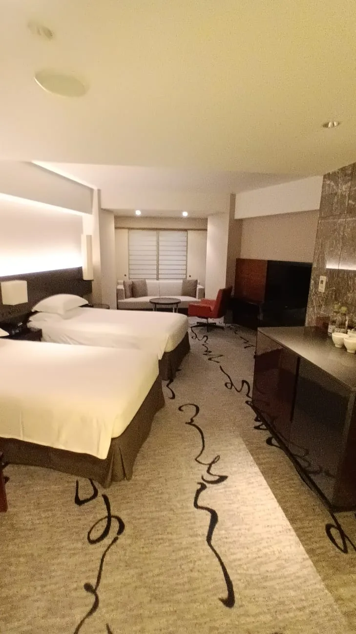 Hotelzimmer mit Doppelbetten und grauem Teppich