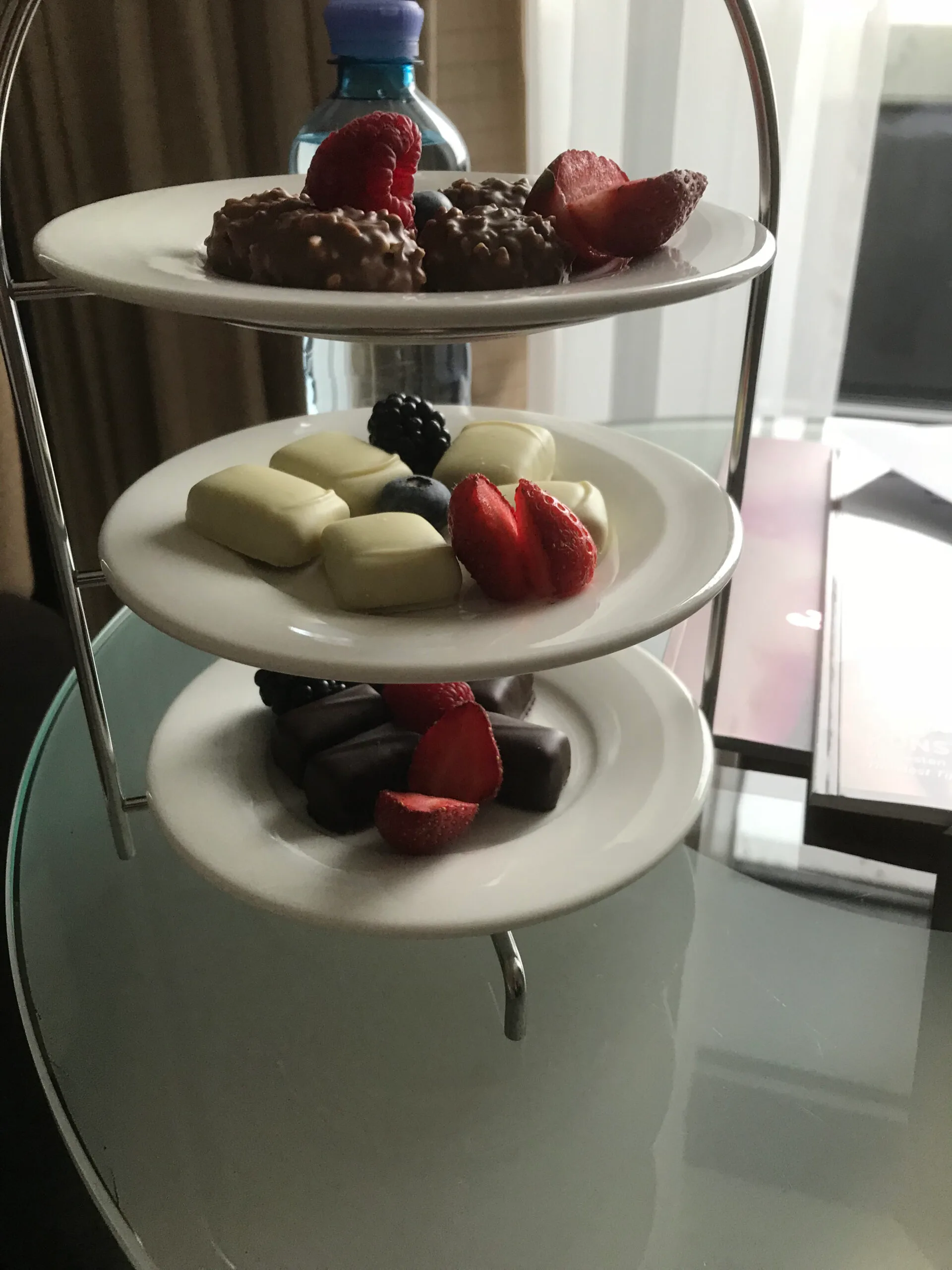 Drei-Teller-Dessert mit Schokoladenkugeln und Früchten auf einem Servierwagen