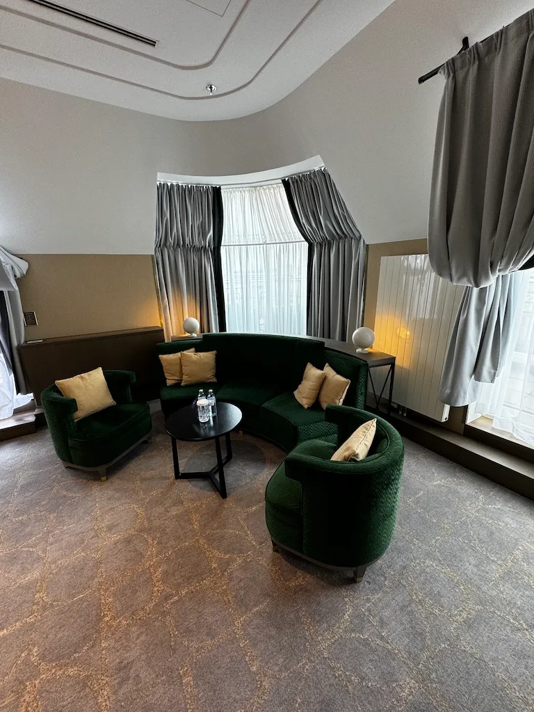 Hotelzimmer mit grüner Couch und Sesseln