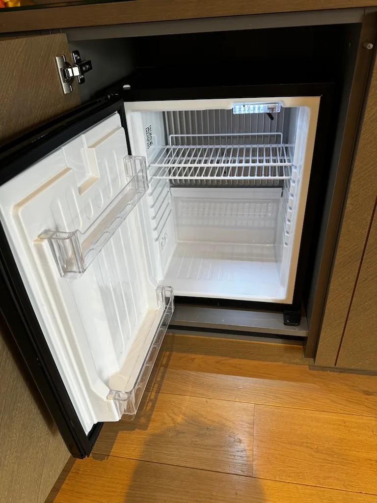 Kleiner Kühlschrank im Zimmer mit leerem Regal