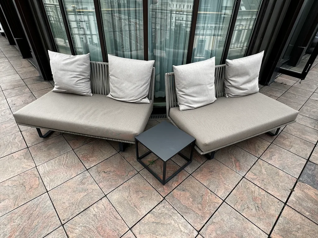 Terrasse mit zwei Sesseln und Kissen vor großen Fenstern