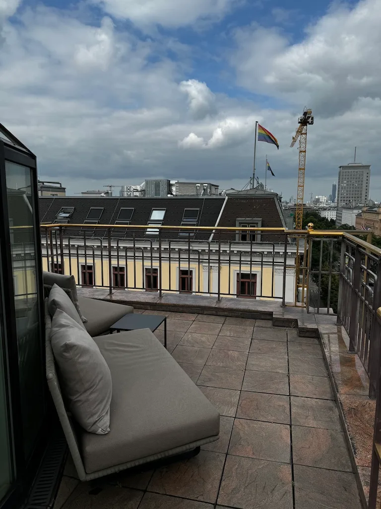 Terrasse mit Sofa und Blick auf Gebäude und Regenbogenfahne