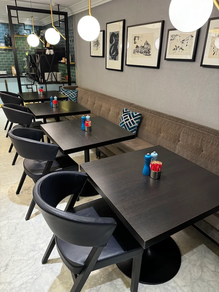 Hotelrestaurant mit schwarzen Tischen und Stühlen, dekorativer Wand mit Bildern