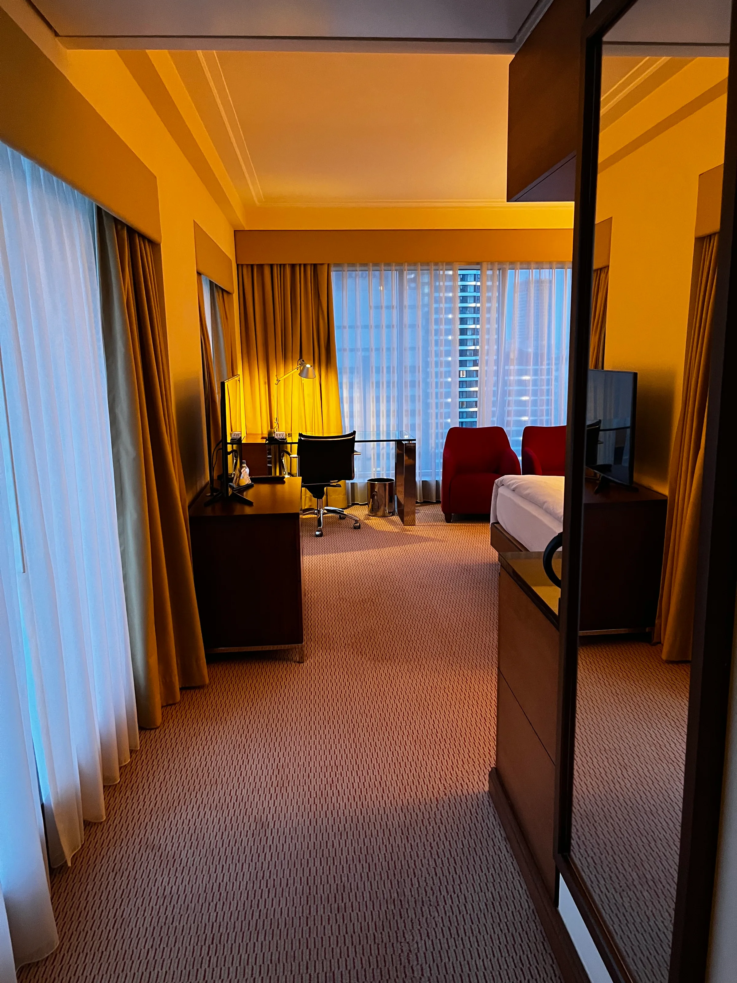 Hotelzimmer mit Doppelbett und roten Sesseln