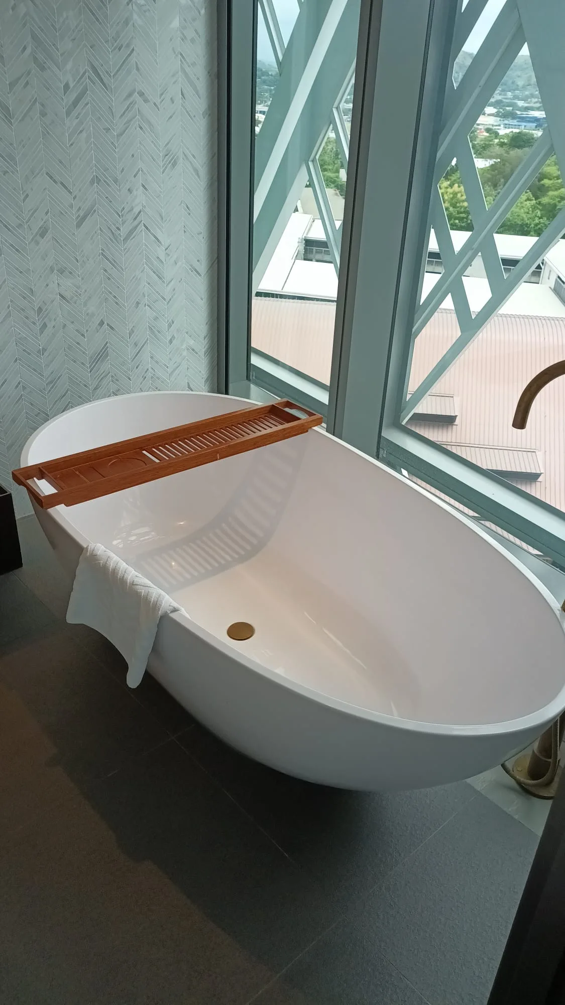 Freistehende Badewanne mit Holzregal und Handtuch im modernen Badezimmer