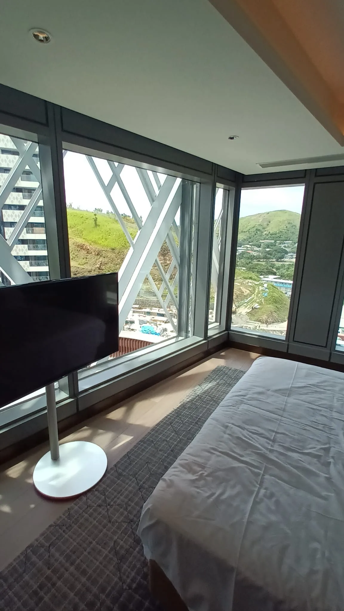 Hotelzimmer mit Doppelbett und großen Fenstern zum Grünen Hügel