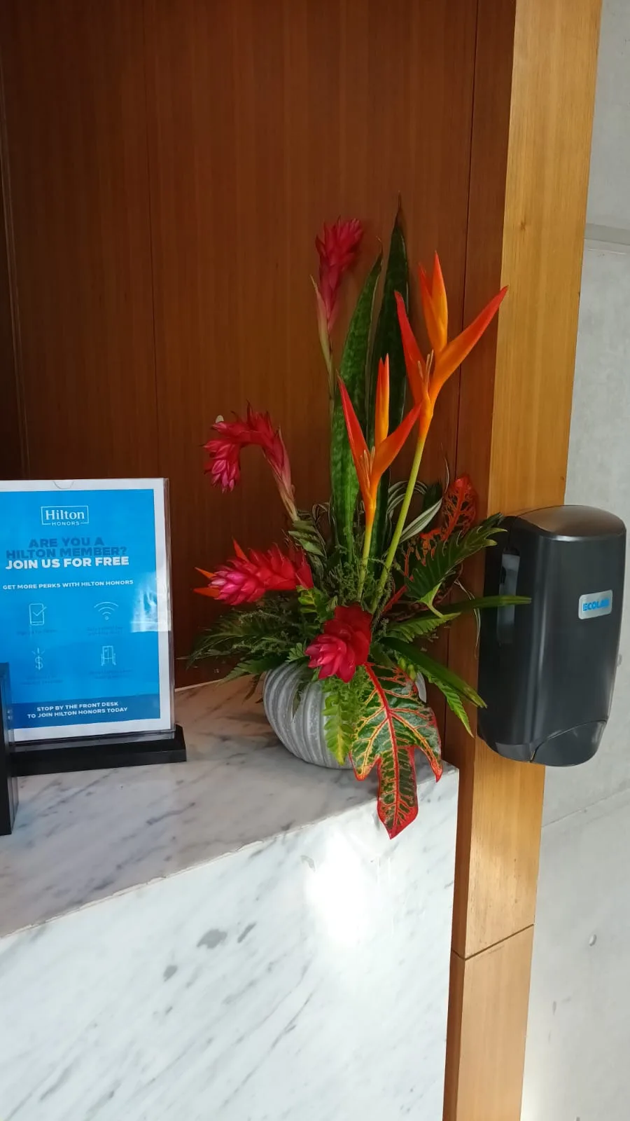 Hotellobby mit Blumenarrangement und Informationsplakat