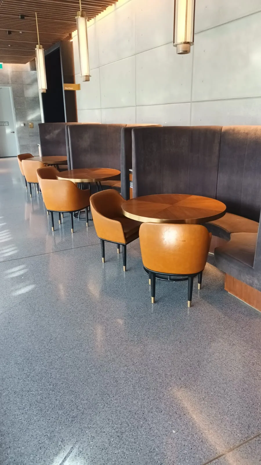 Hotellobby mit runden Tischen und braunen Stühlen