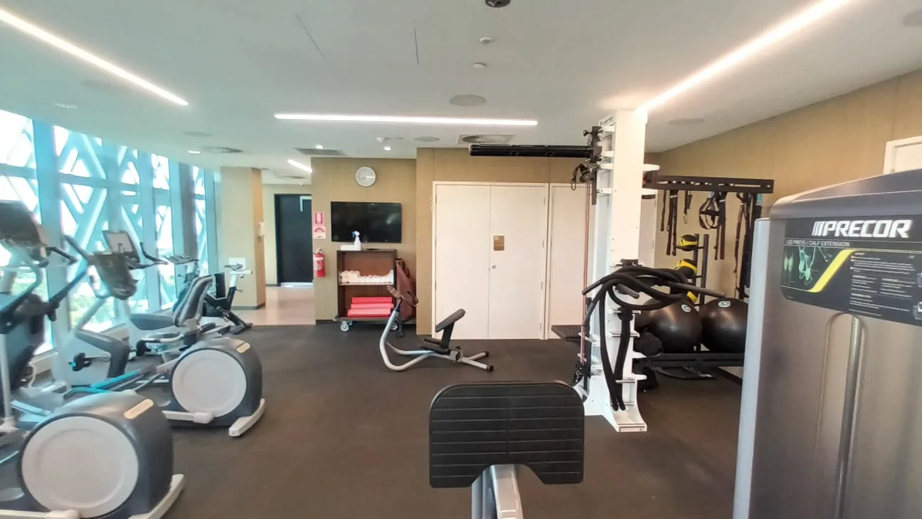 Fitnessraum mit verschiedenen Trainingsgeräten und Fernseher