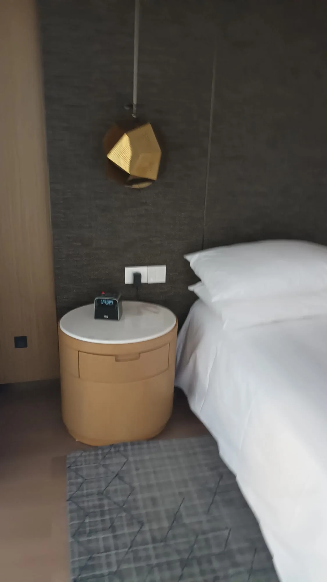 Hotelzimmer mit Nachttisch und Bett in Grautönen