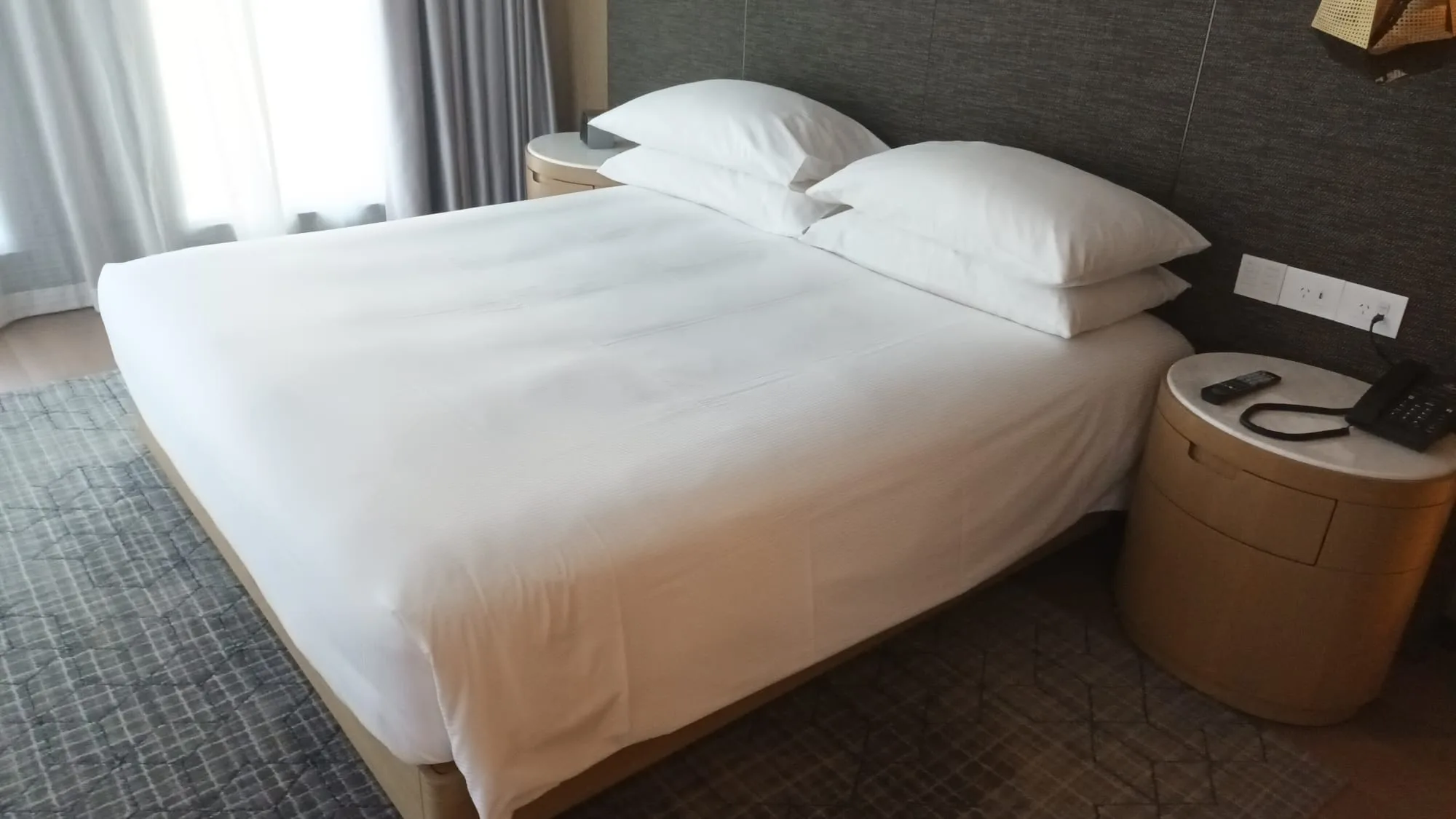 Hotelzimmer mit Doppelbett und grauem Tagesdeckenmuster