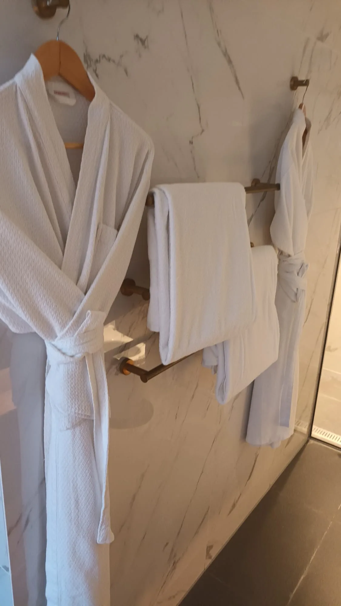 Handtuchhalter mit Handtüchern und Bademantel an Wand