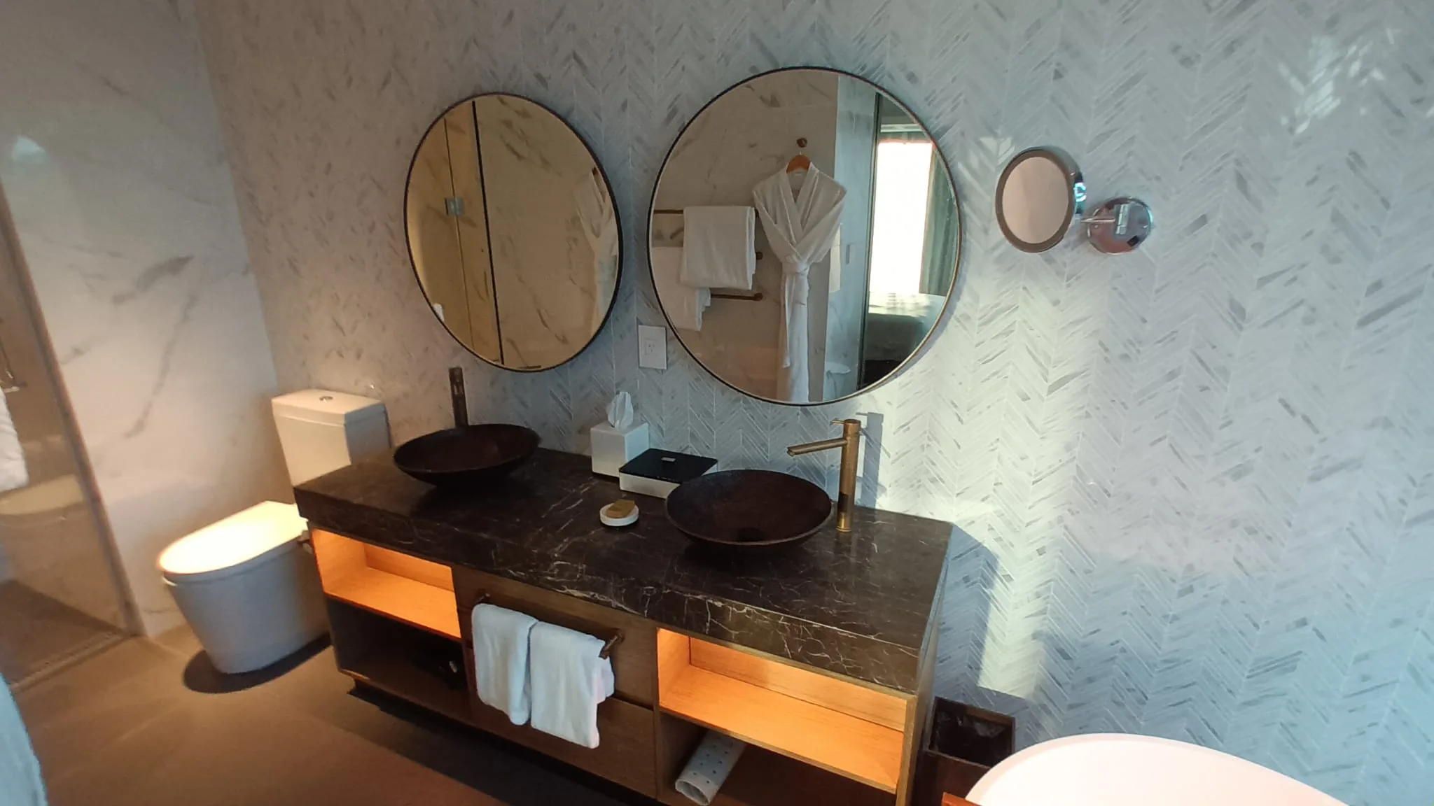 Moderne Badezimmeranlage mit Doppelwaschbecken und runden Spiegeln