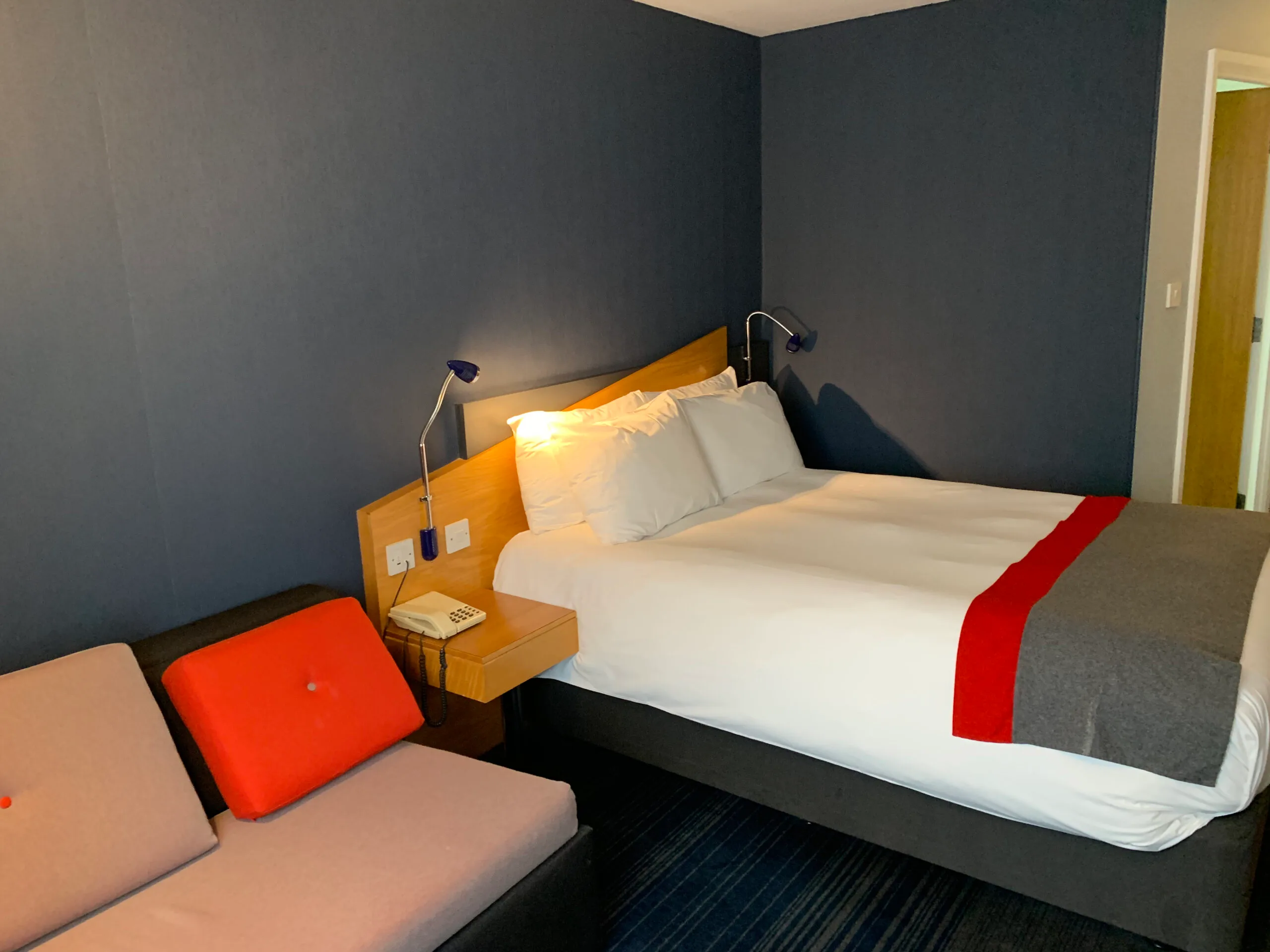 Hotelzimmer mit Doppelbett und Nachttisch in Grautönen