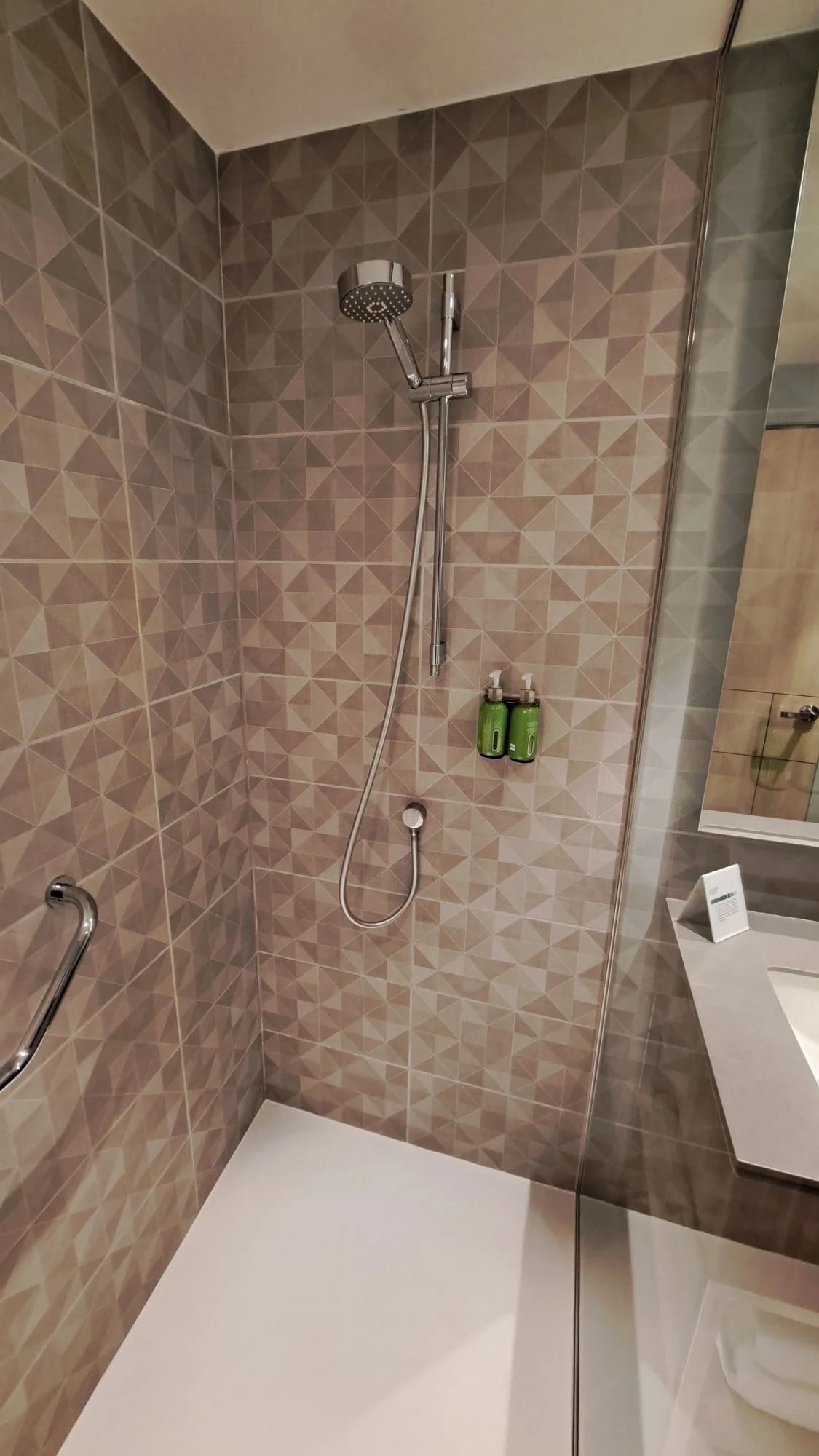 Duschbereich mit geometrischer Fliesenoptik und Handbrause