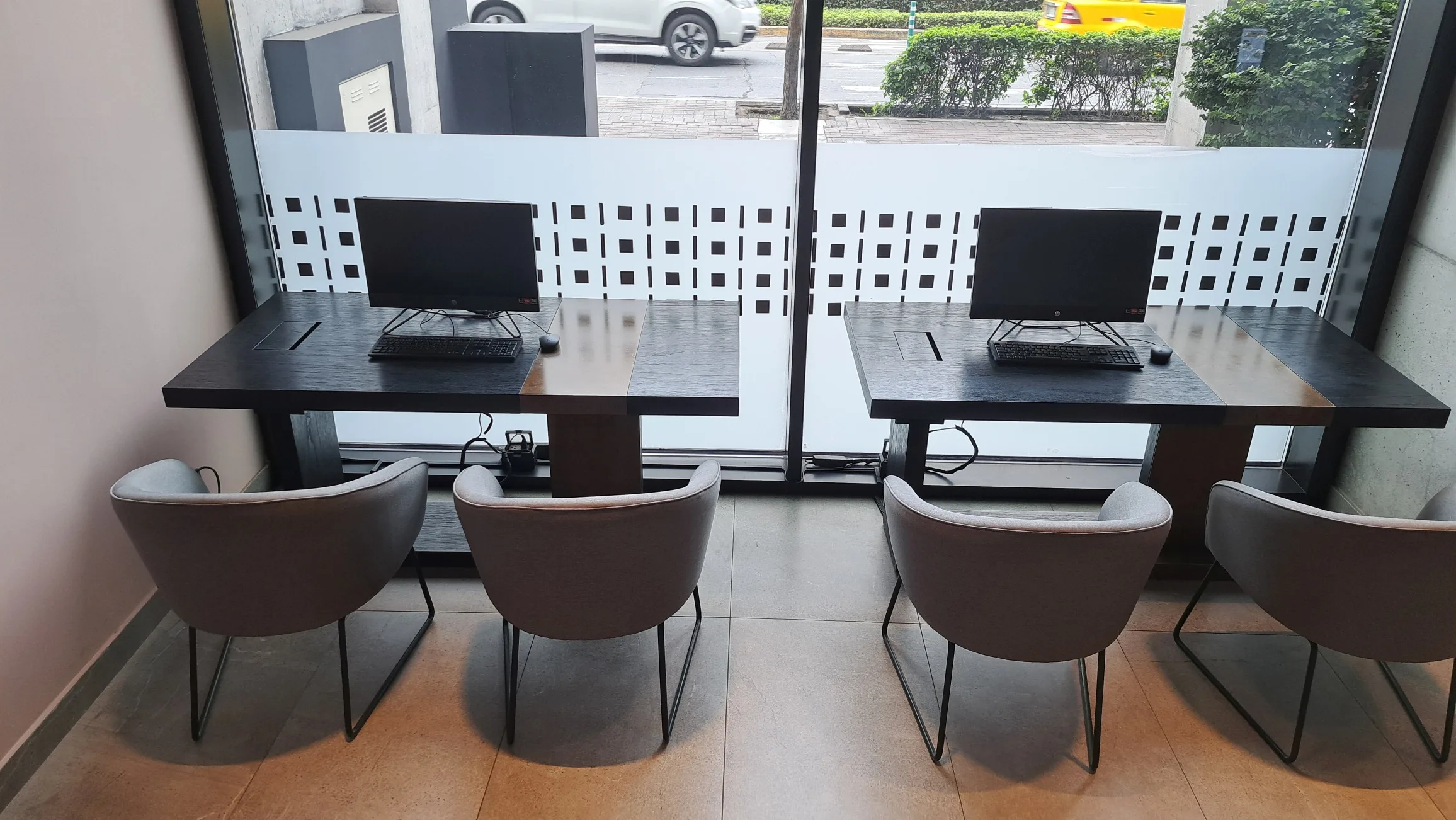 Zwei Arbeitsplätze mit Computern und Stühlen vor Fenster