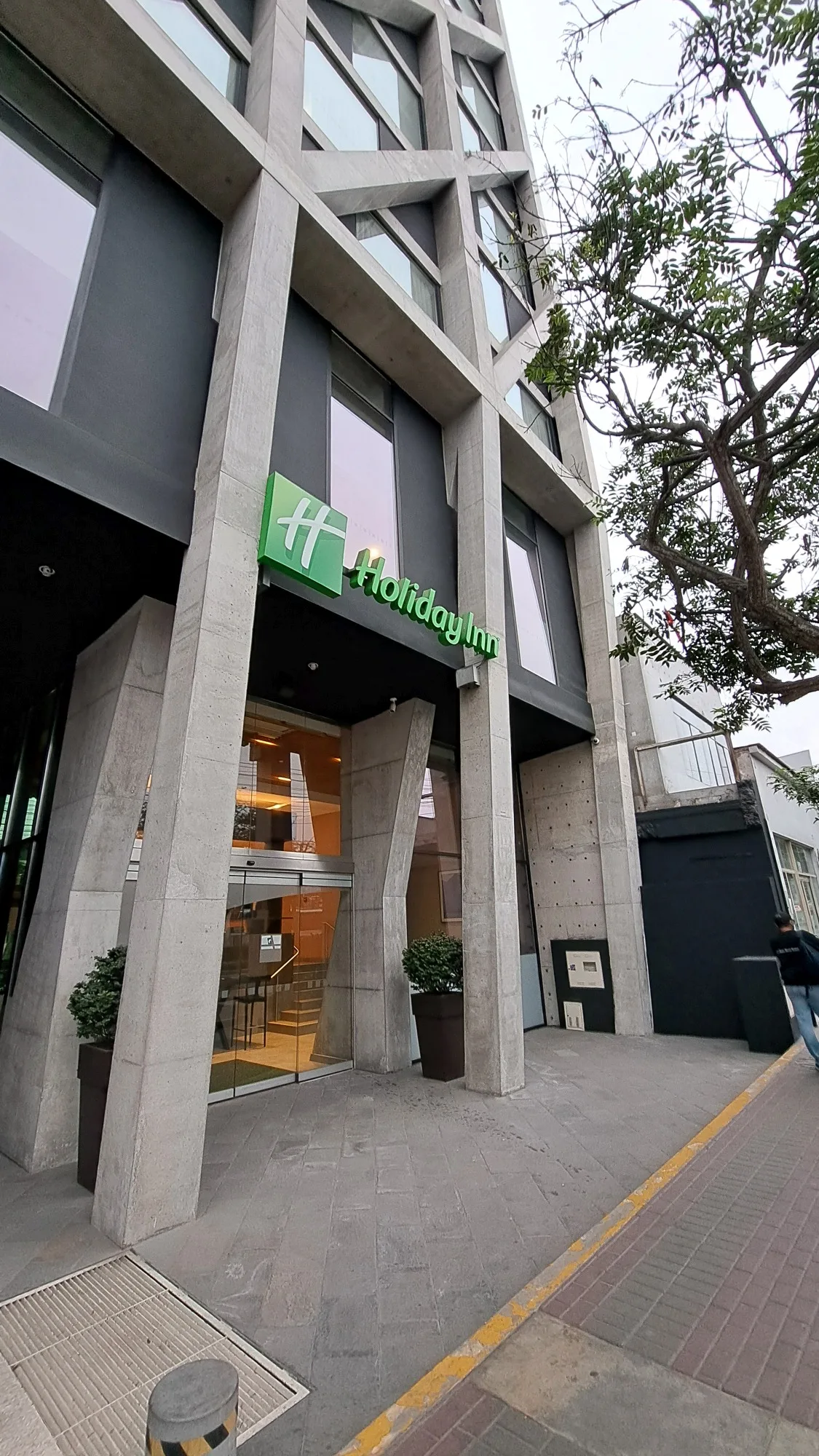 Holiday Inn Eingang mit Pflanzen und grauem Fassadengestaltung