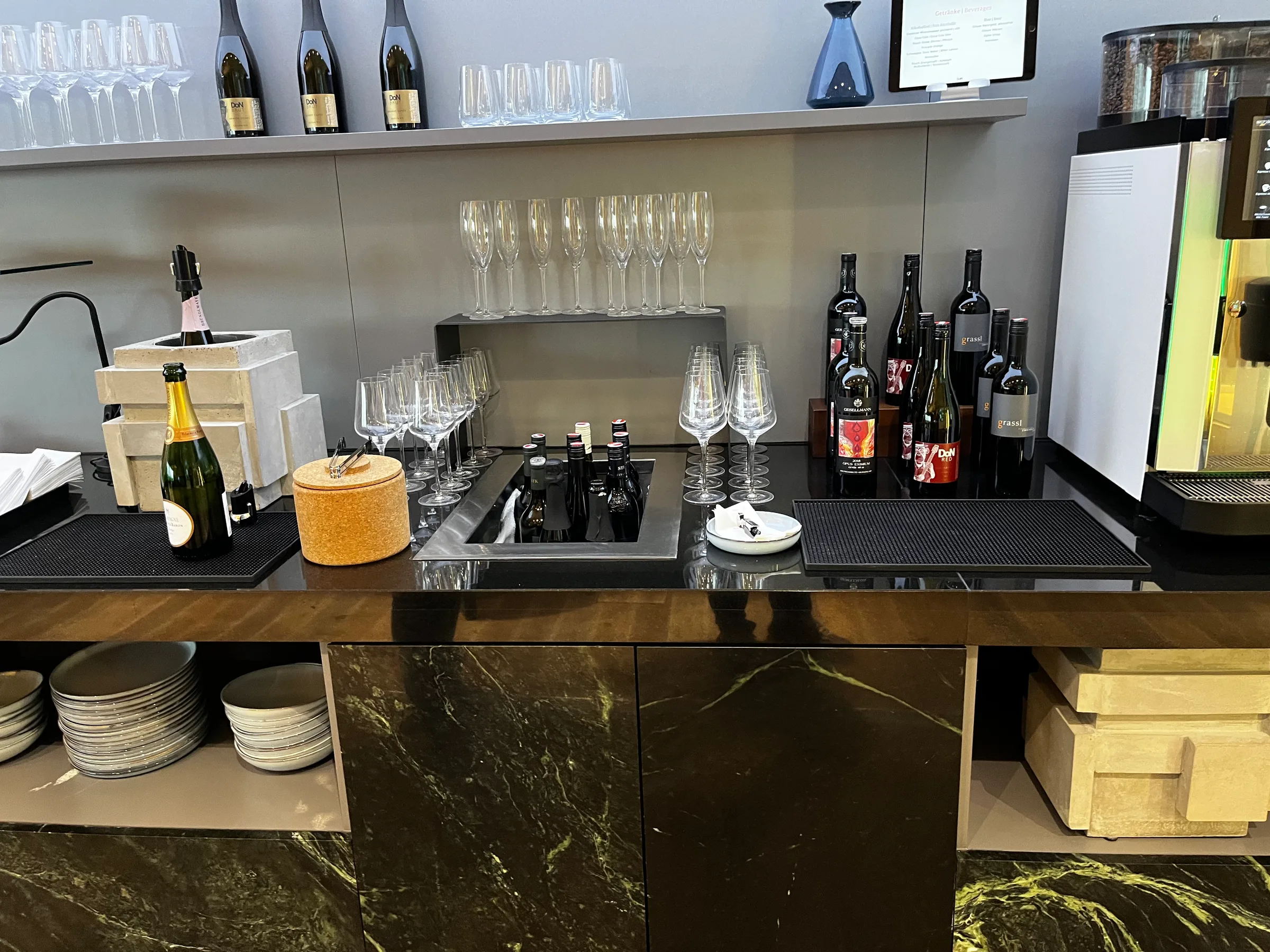 Bar mit Champagnerflaschen und Weingläsern im Flughafen Wien Lounge