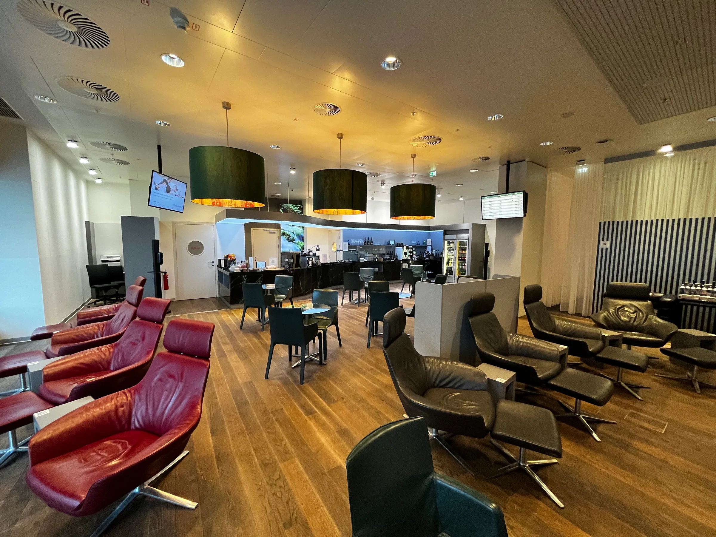 Lounge mit roten Sesseln und grünen Lampenschirmen