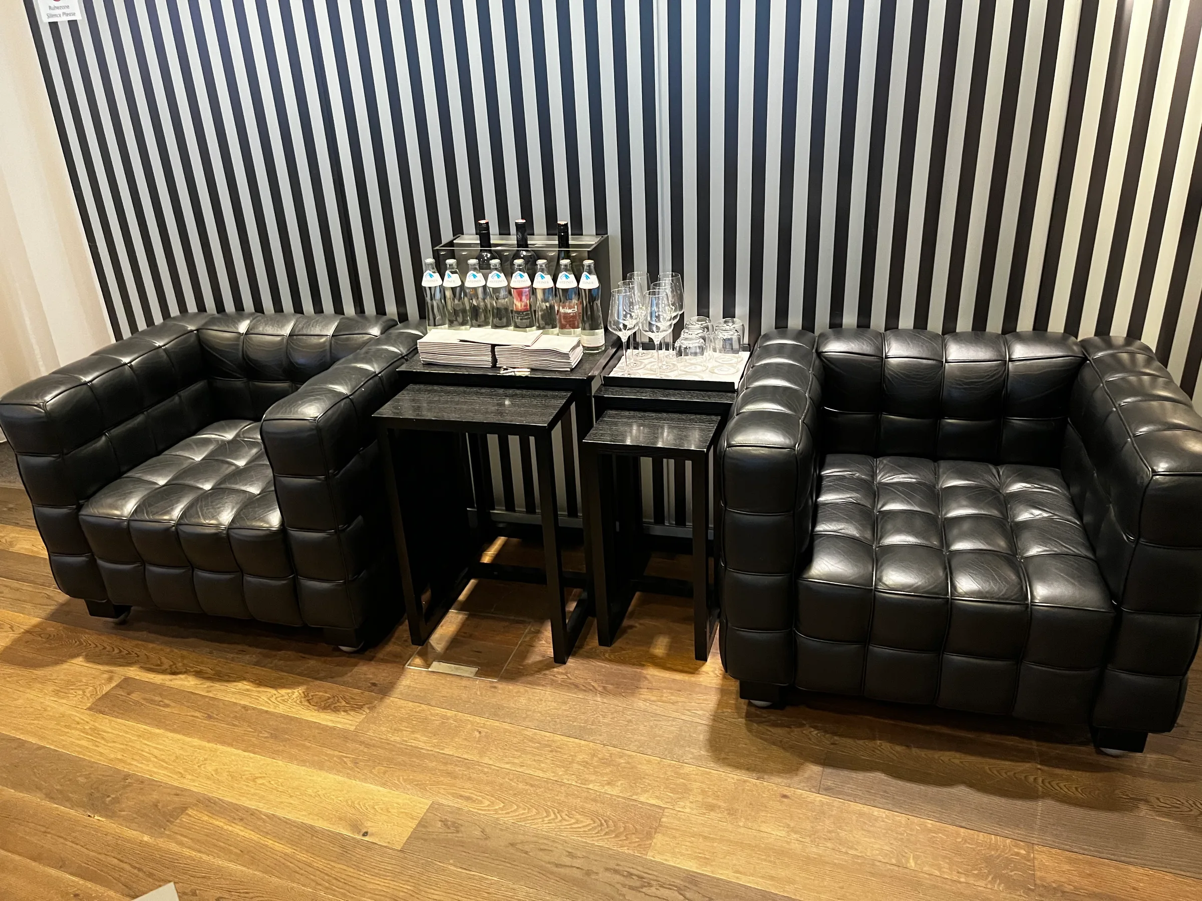 Schwarze Ledersofa und Couchtisch vor gestreiftem Wandhintergrund