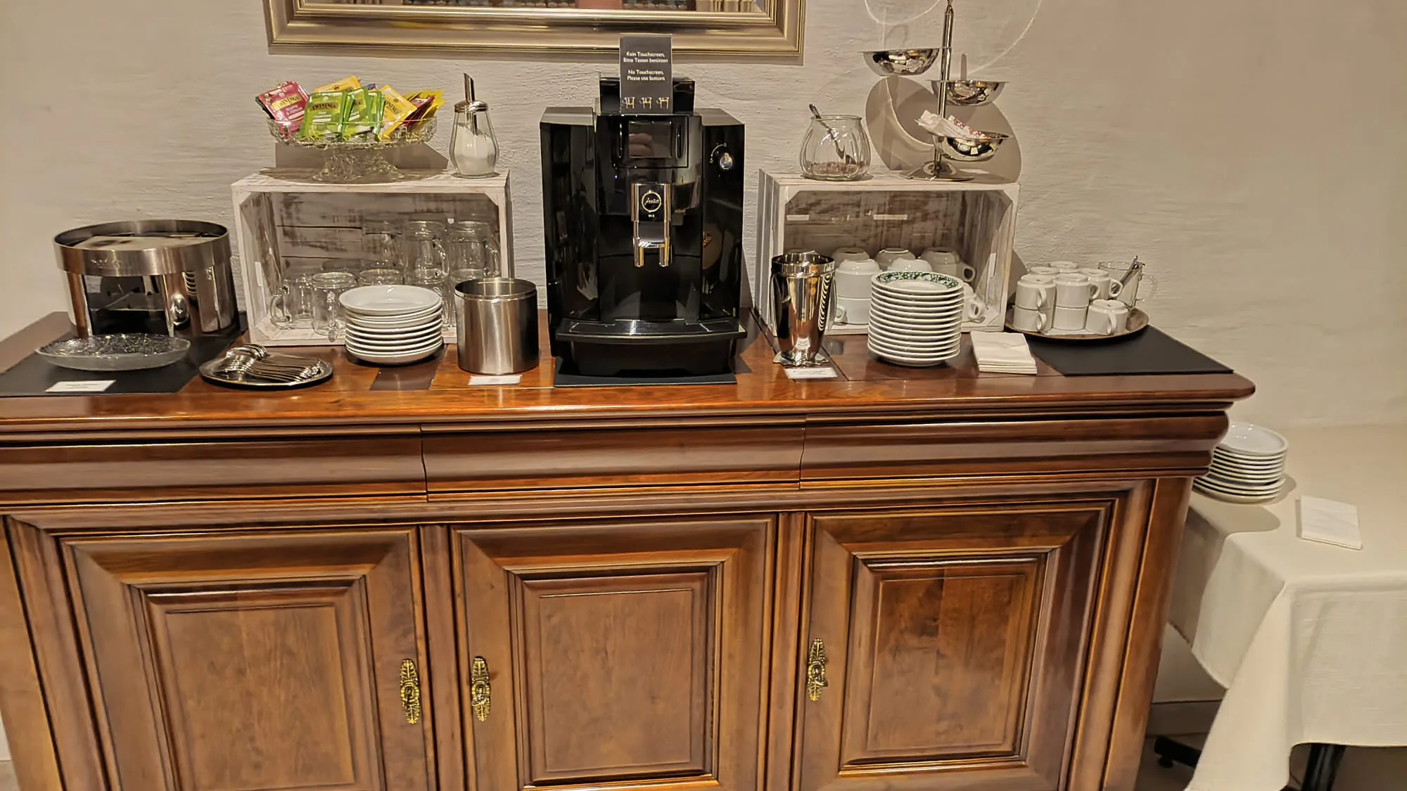 Kaffeeautomat und Geschirr auf Holzkommode im Hotel