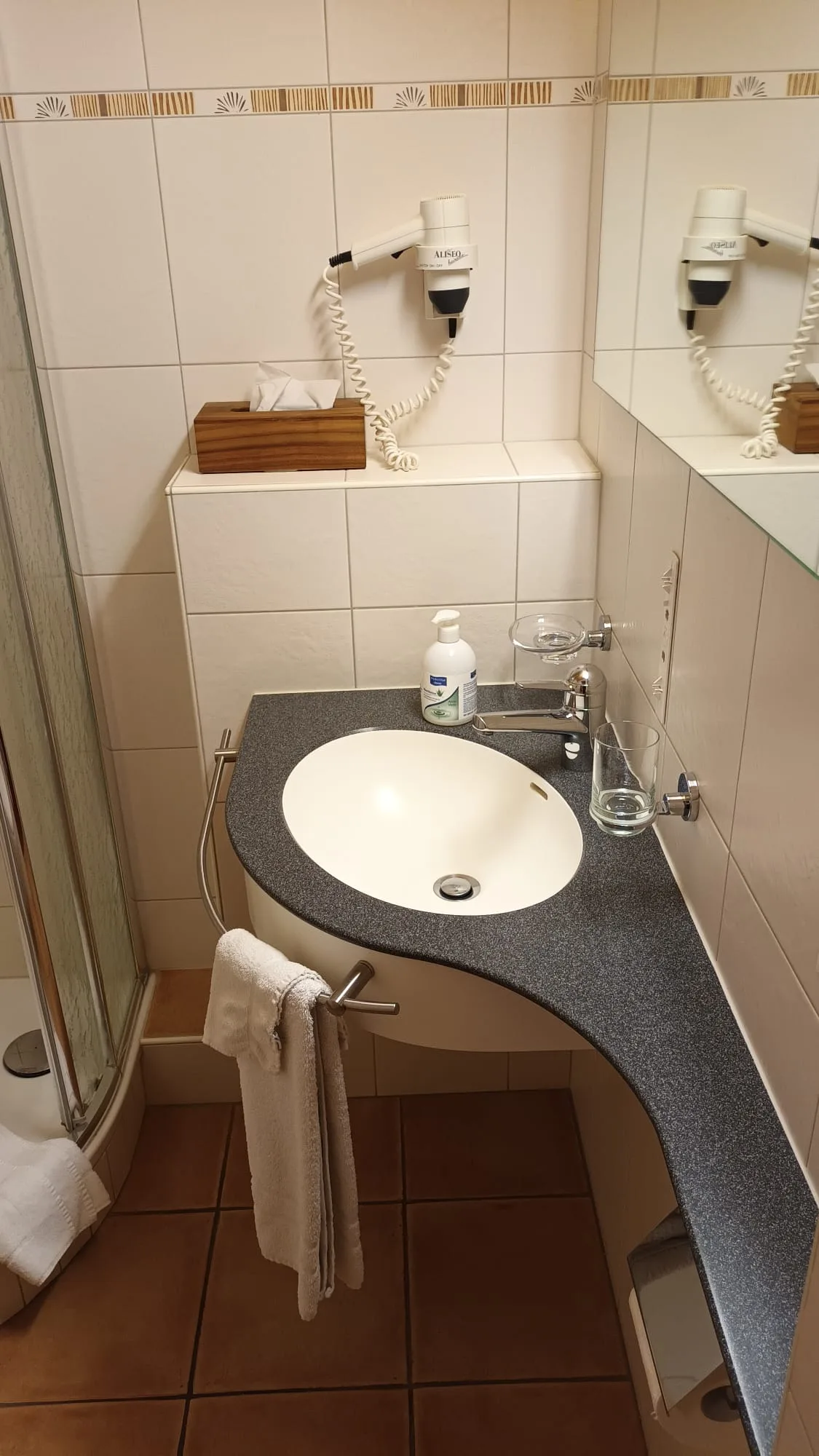 Hotelbadezimmer mit Waschbecken, Spiegel und Handtuchhalter