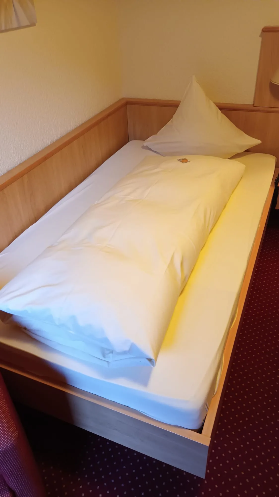 Einzelbett im Hotelzimmer mit weißer Bettwäsche