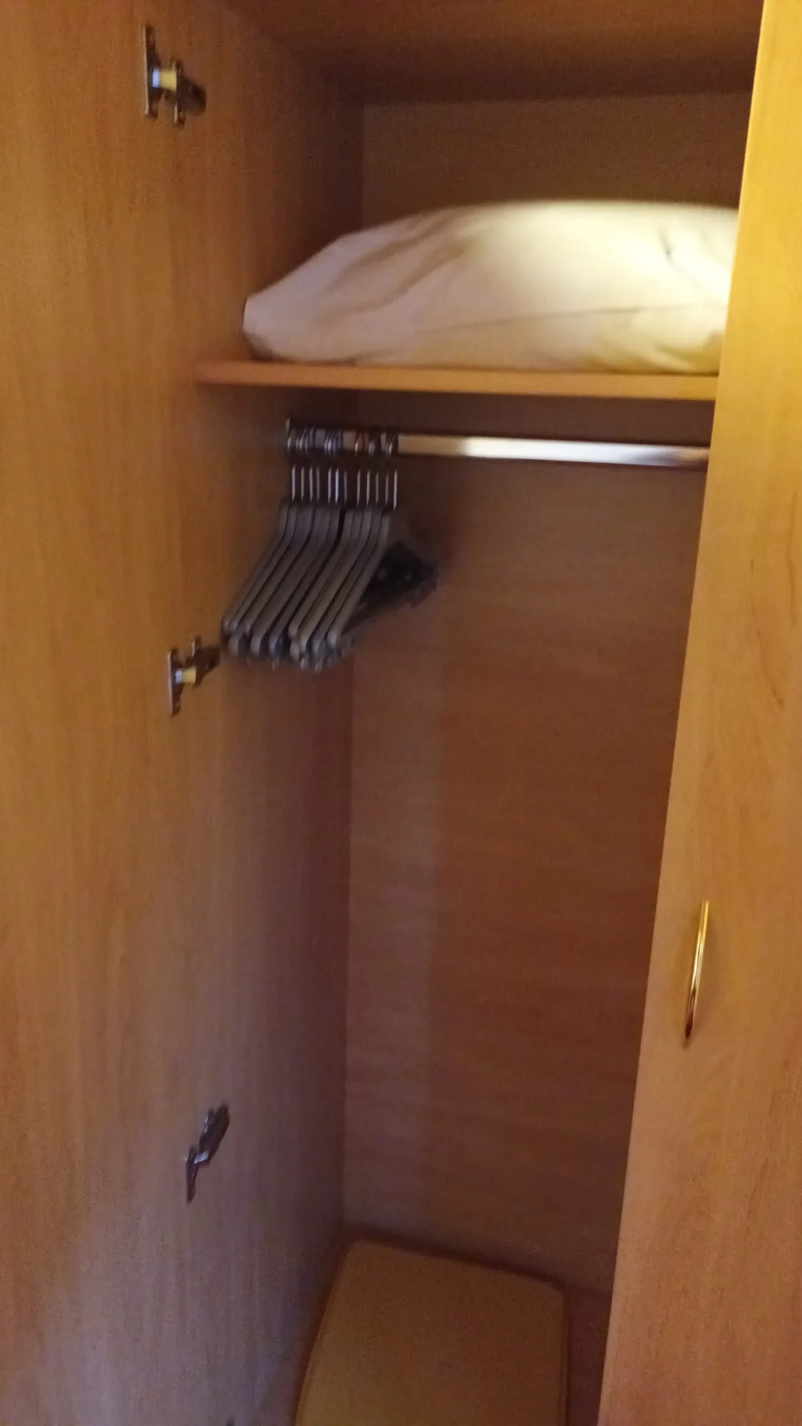 Schrank mit Kleiderbügeln und Bettdecke
